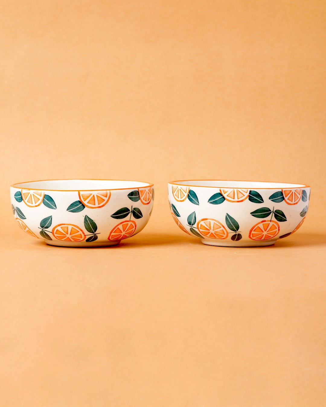 Two ceramic bowls with fruit pattern on a beige background