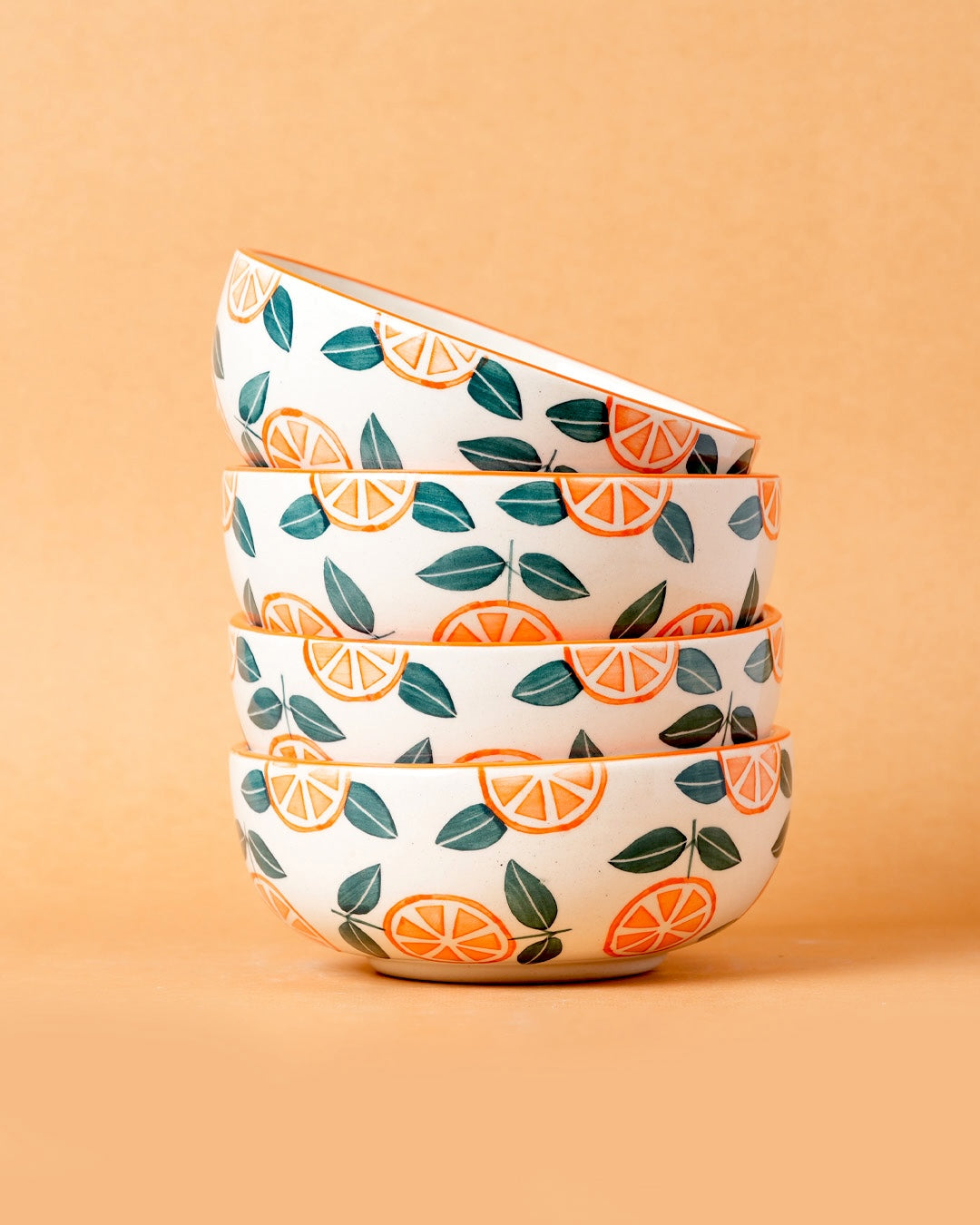 Set of four ceramic bowls with orange and leaf pattern on a beige background