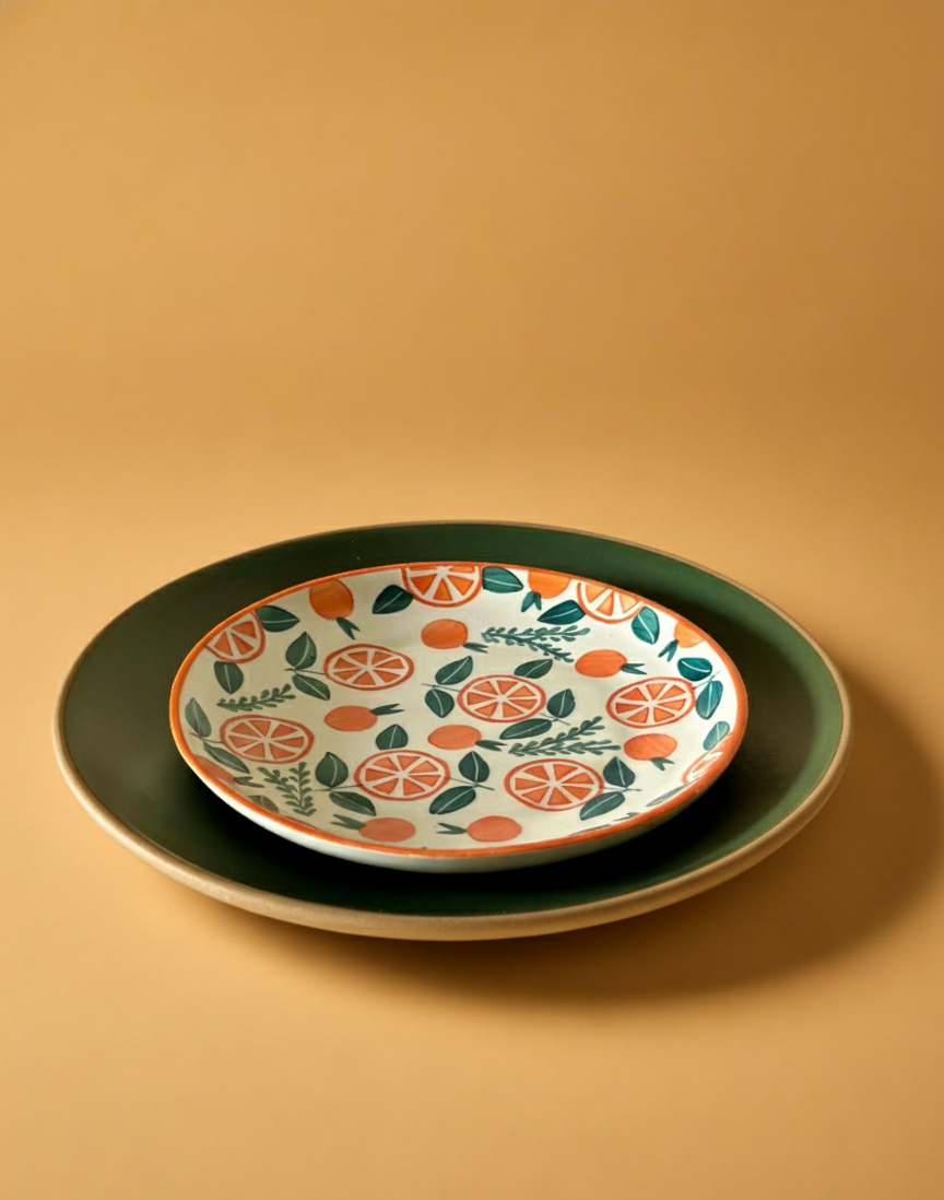Decorative plate with orange pattern on a matching platter against a beige background
