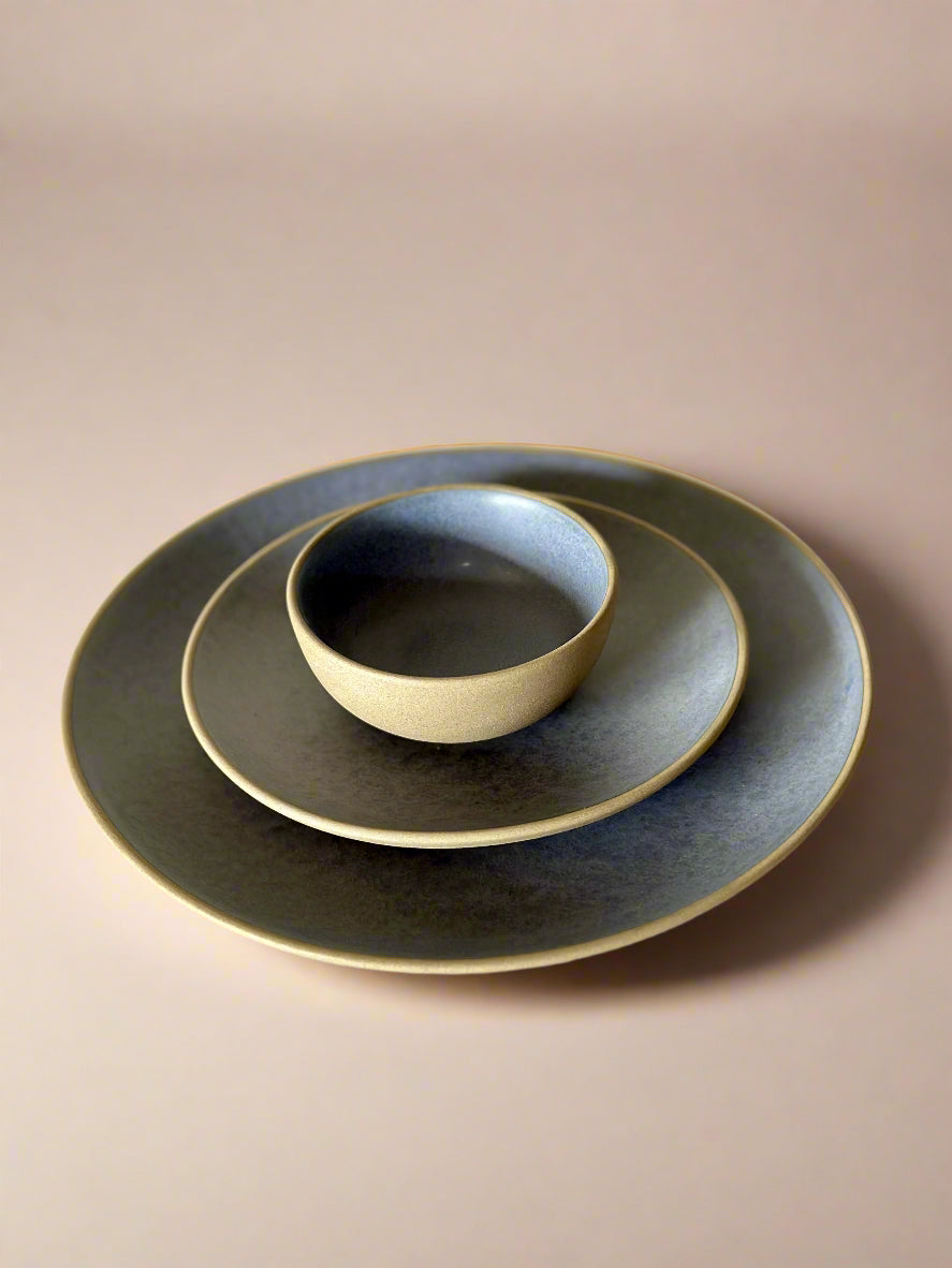 Set of dark ceramic plates and bowl on a light surface
