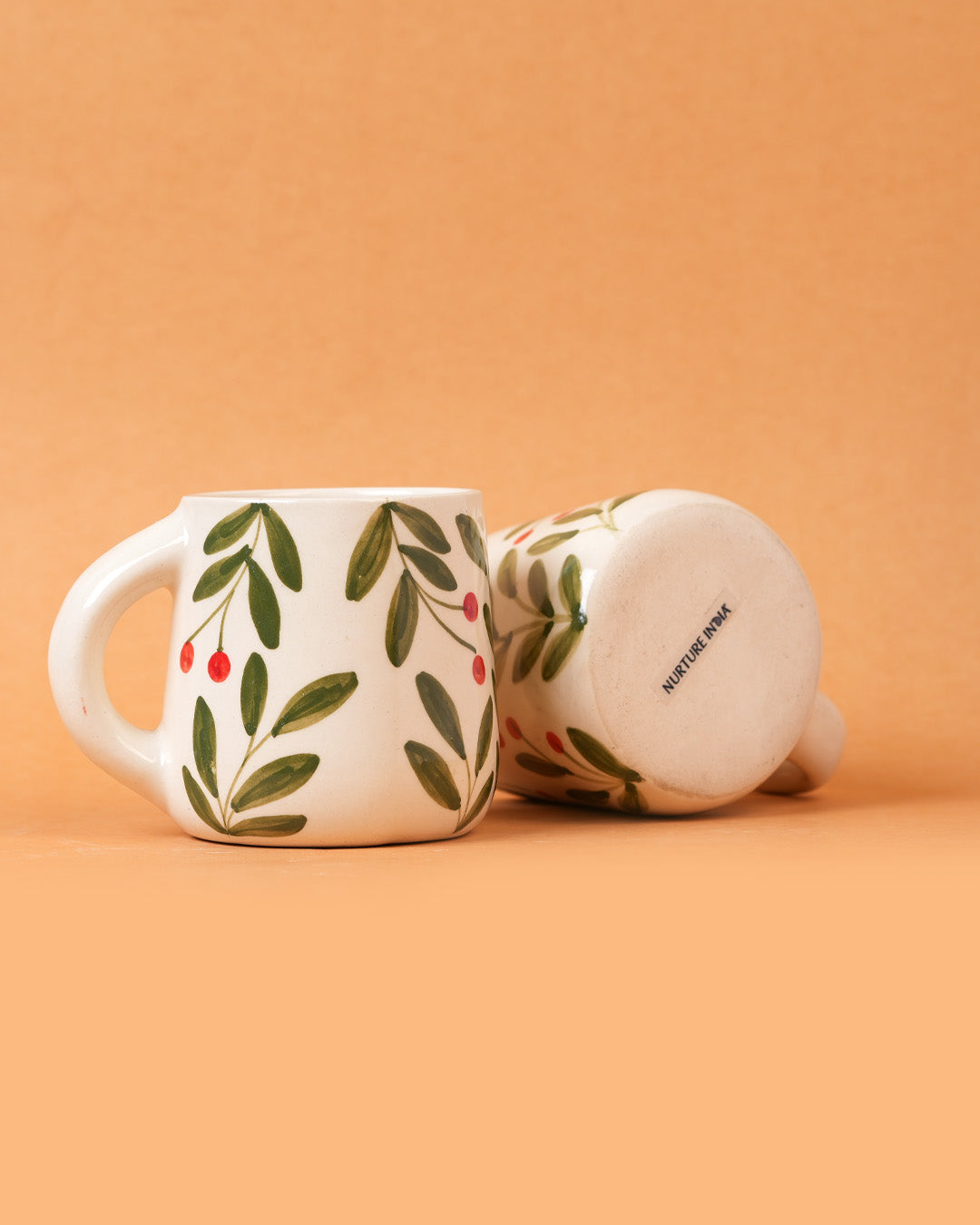 Two ceramic mugs with leaf pattern on a beige background