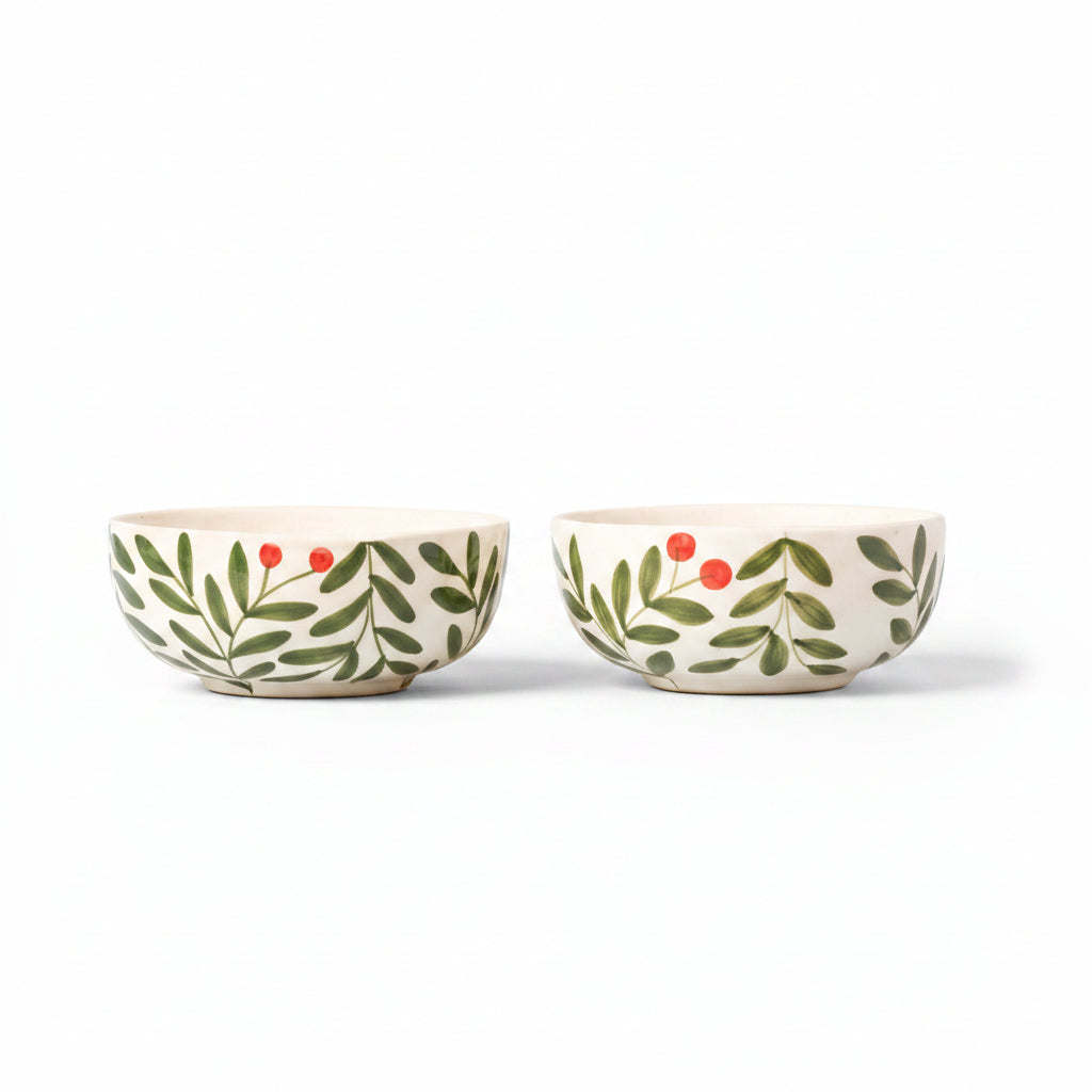 Two ceramic bowls with leaf and berry design on a beige background