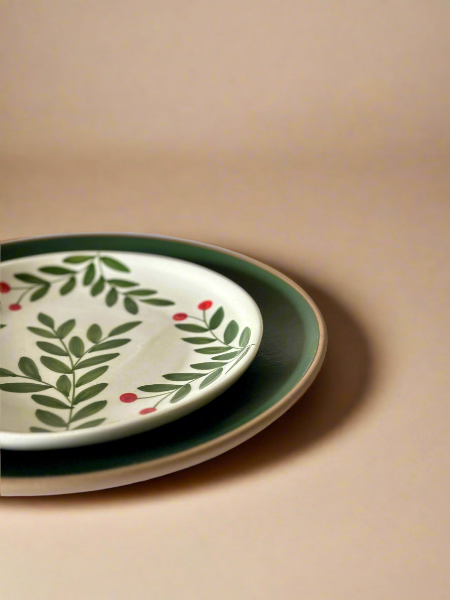 Two ceramic plates with leaf and berry design on a beige background