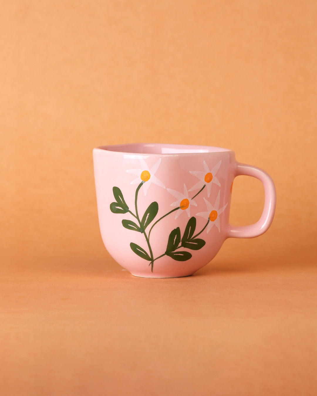 Pink mug with floral design on a peach background