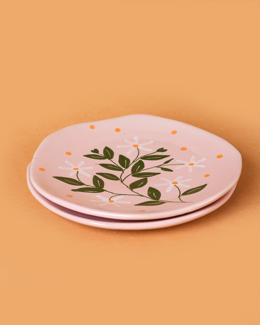 Set of pink ceramic plates with floral design on a beige background