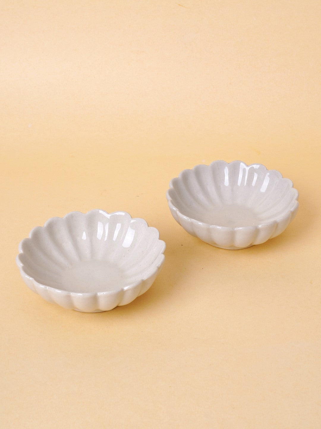 Two white ceramic bowls with a scalloped edge design, displayed against a neutral background.