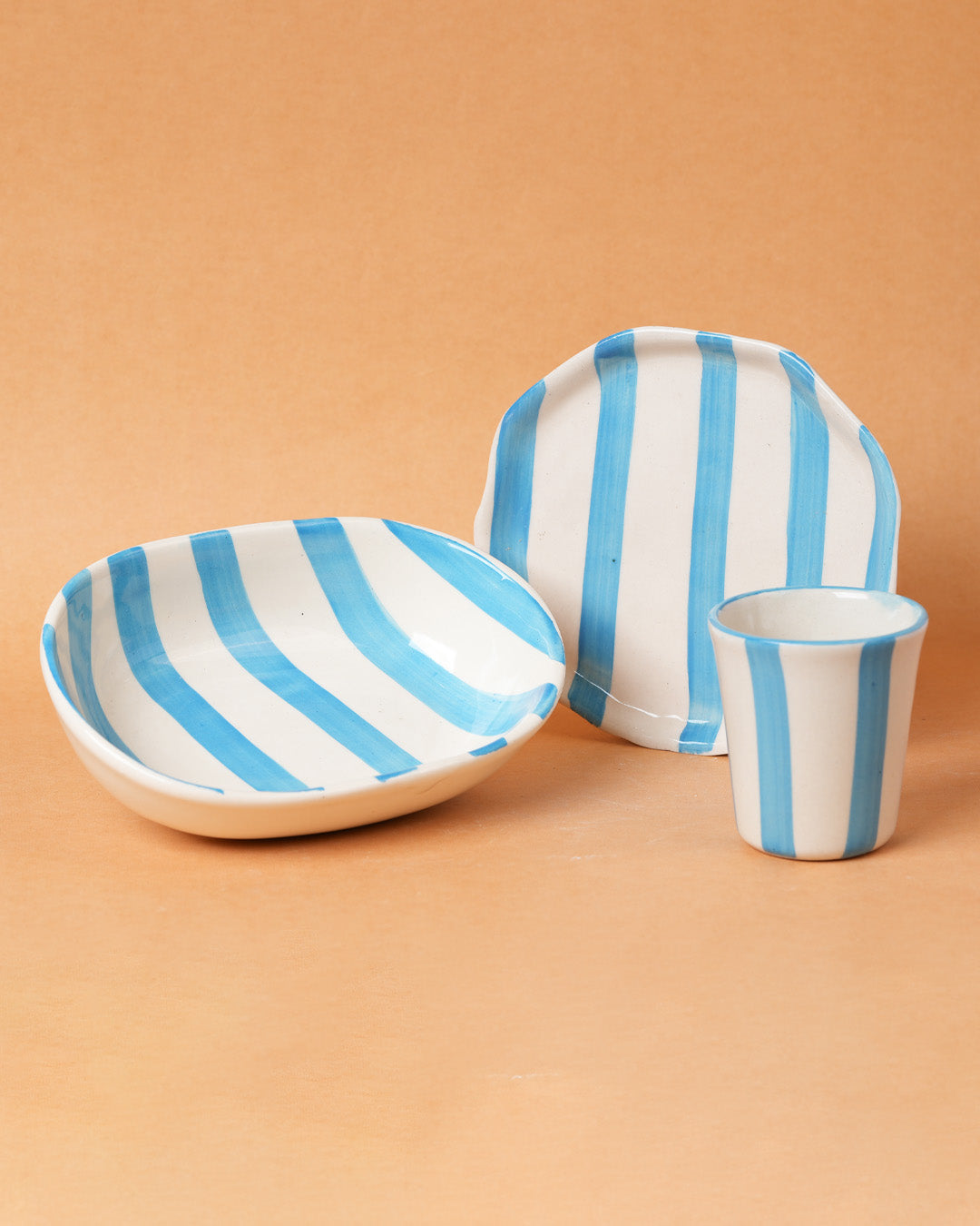 Ceramic tableware set with blue and white stripes on a beige background