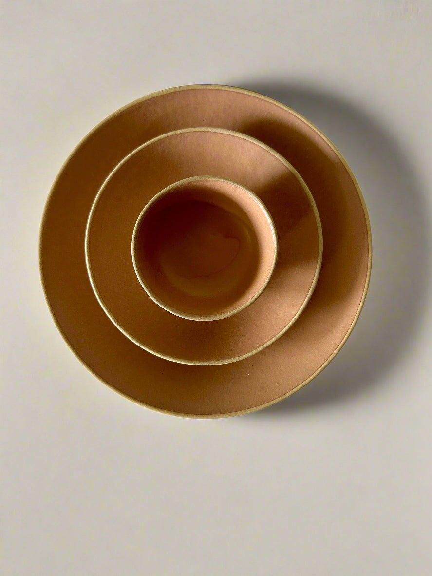 Set of three brown ceramic bowls on a white surface