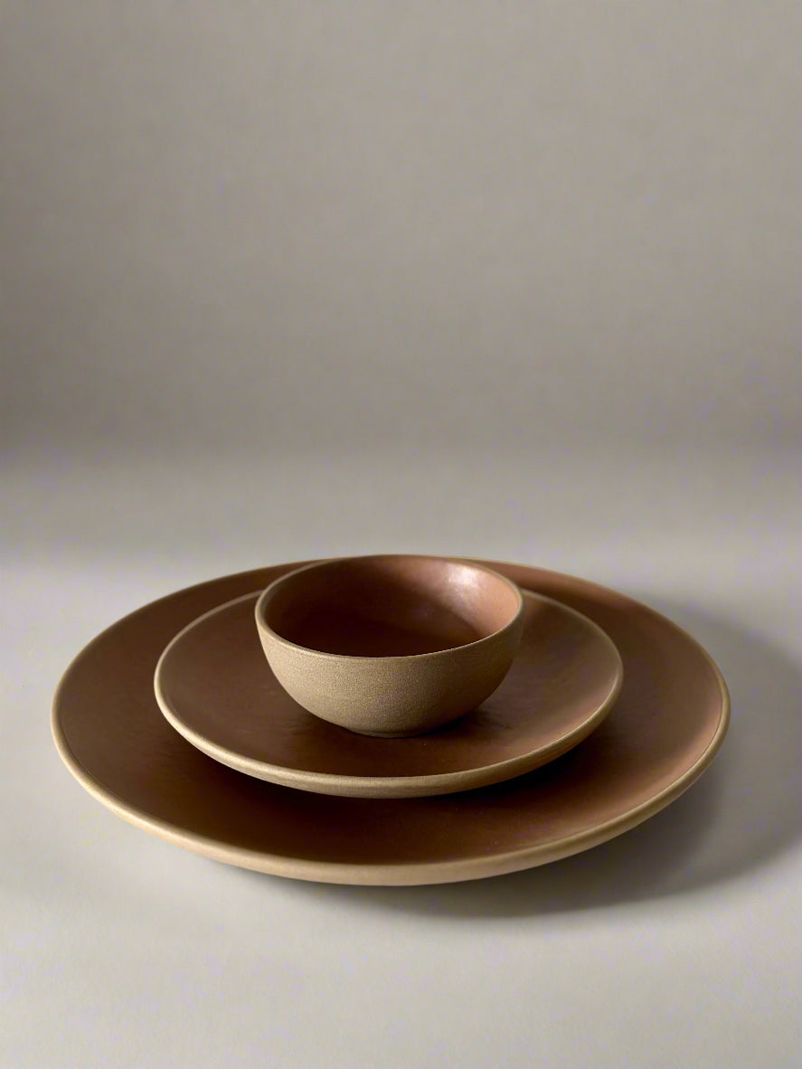 Set of brown ceramic dishes on a light surface with a white background