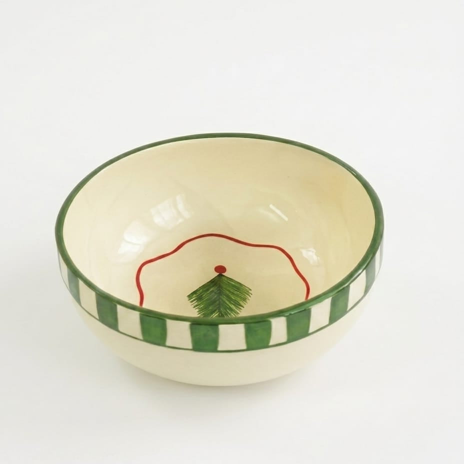 Ceramic bowl with green and white striped rim and red design on a white background