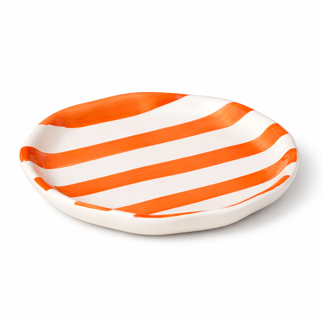 Oval ceramic plate with orange and white stripes on a white background