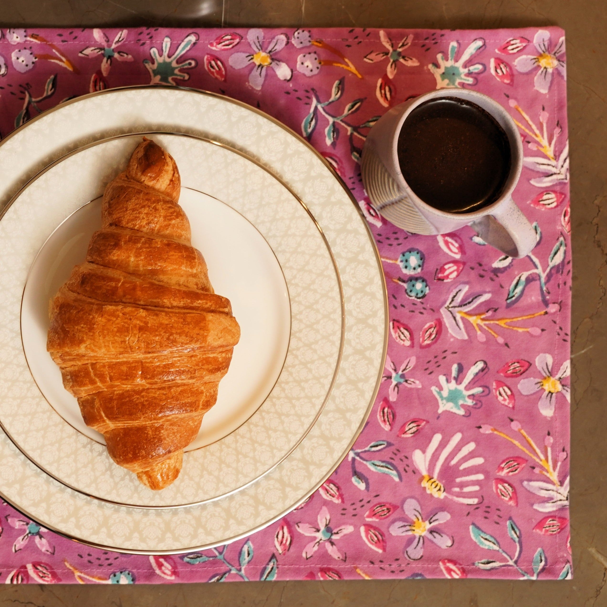 a croissant on a plate next to a cup of coffee