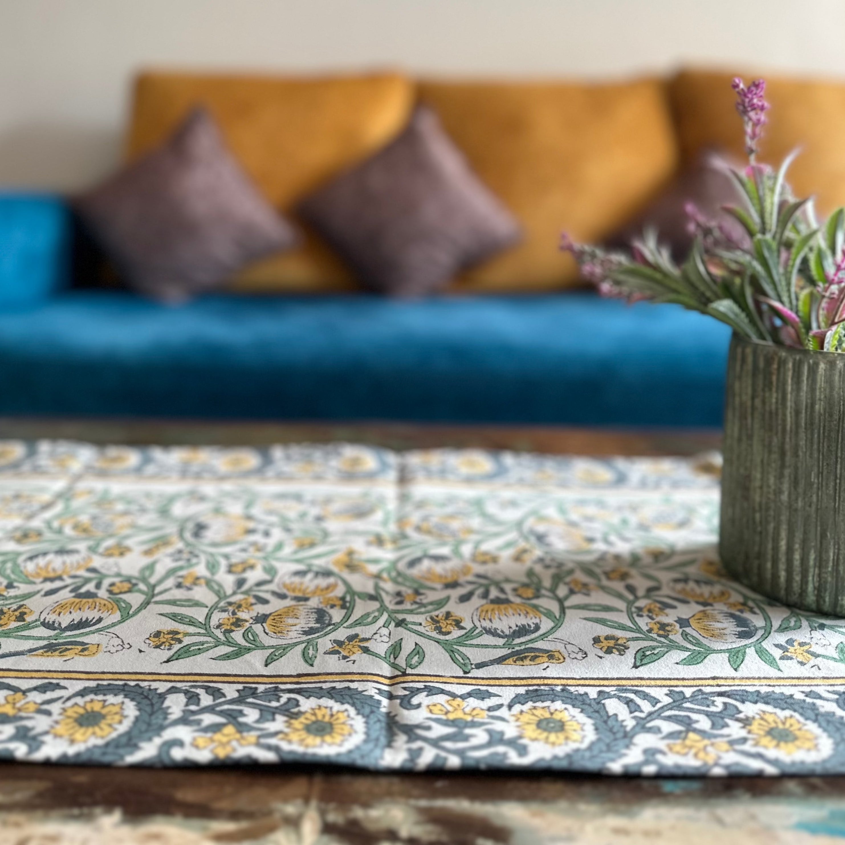 a living room with a blue couch and a plant in a vase